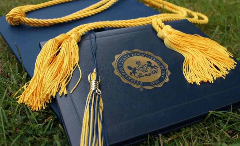 blue diploma cover with penn state university seal and a blue graduation cap with gold tassel 
