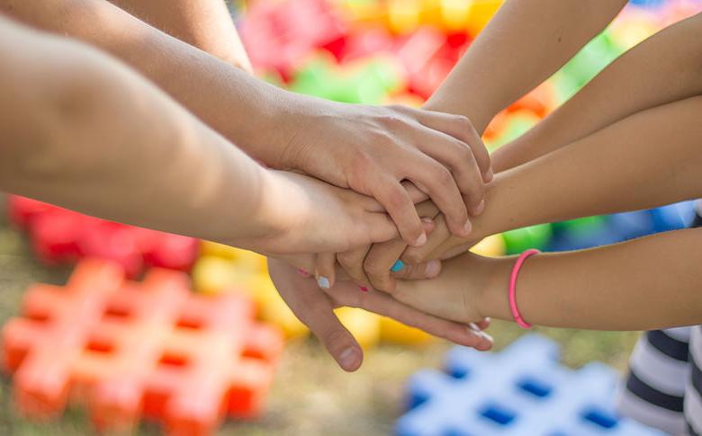 group of children's hands stacked on top of one another signaling unity